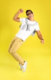 Photo of Handsome young man dancing on yellow background