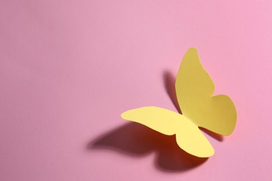 Yellow paper butterfly on pink background, top view. Space for text