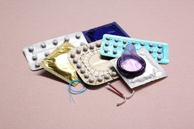 Photo of Contraceptive pills, condoms and intrauterine device on beige background. Different birth control methods