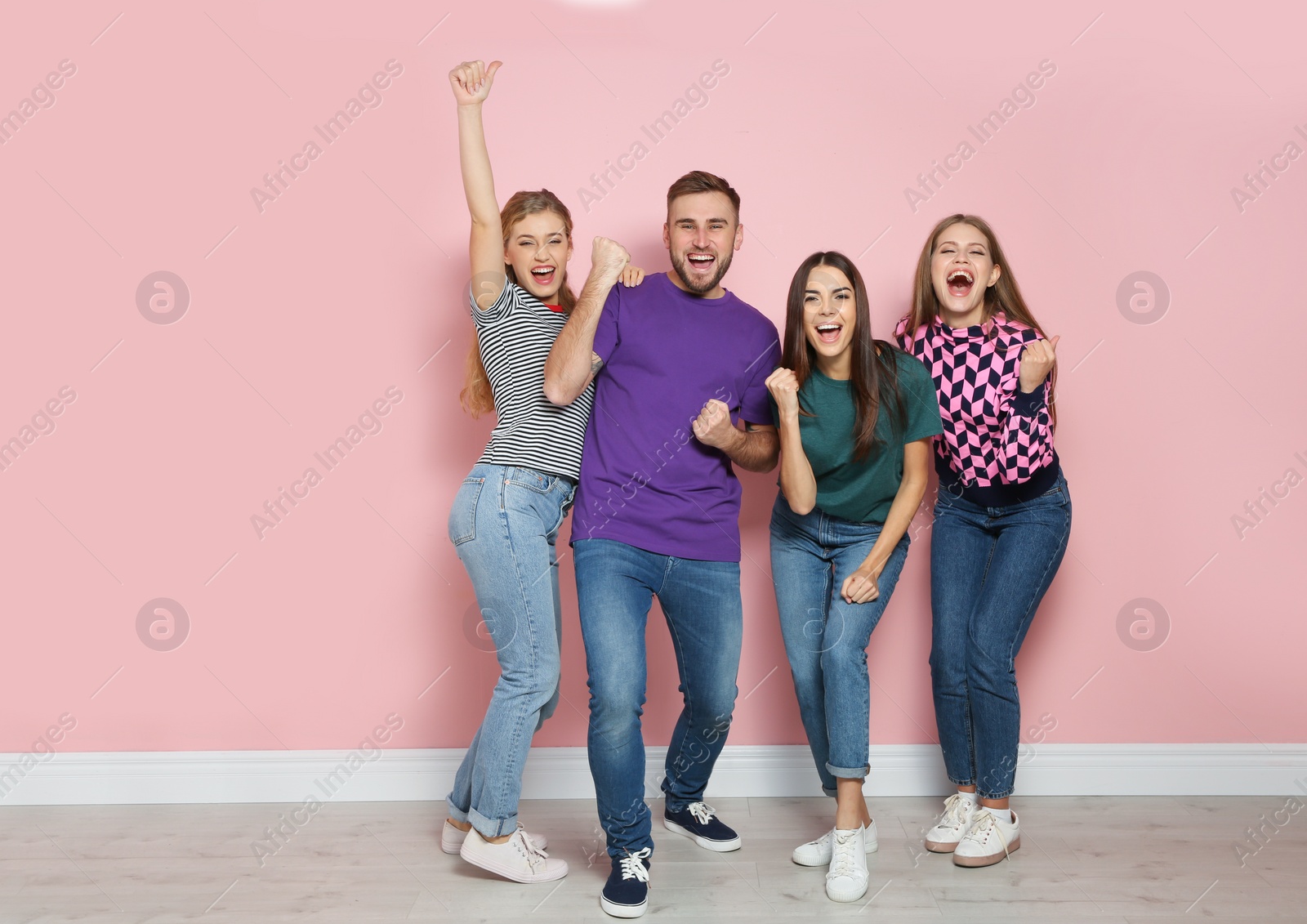 Photo of Young people celebrating victory near color wall. Space for text