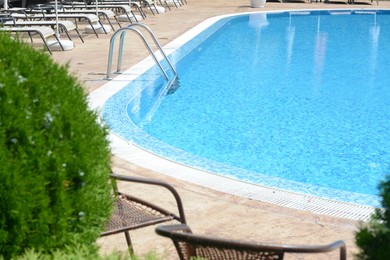 Photo of Outdoor swimming pool with ladder and sunbeds on sunny day