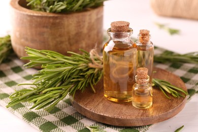 Photo of Essential oil in bottles and rosemary on table