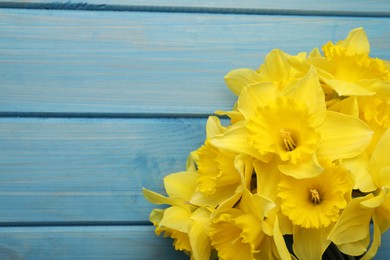 Beautiful daffodil bouquet on blue wooden table, closeup. Space for text
