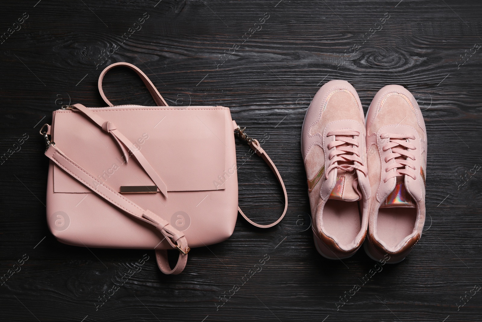 Photo of Stylish shoes and small woman's bag on black wooden table, flat lay