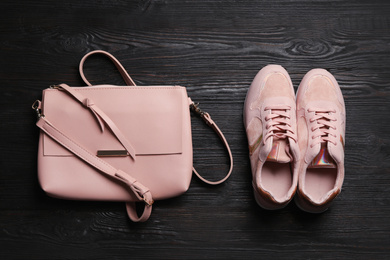 Photo of Stylish shoes and small woman's bag on black wooden table, flat lay