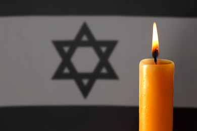 Image of Burning candle against flag of Israel, closeup