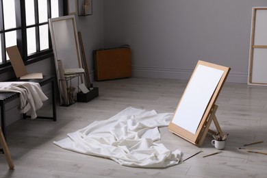 Stylish artist's studio interior with canvas, white fabric and brushes