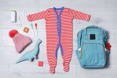 Flat lay composition with baby accessories and maternity backpack on wooden background