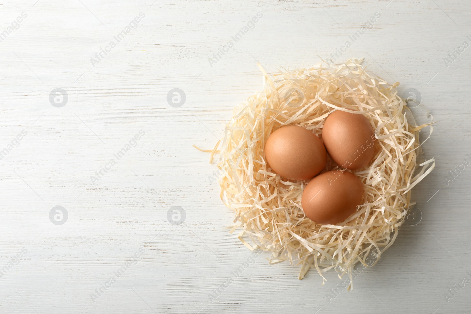 Photo of Nest with eggs and space for text on wooden background, top view. Pension concept