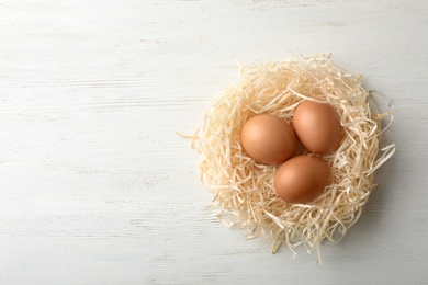 Photo of Nest with eggs and space for text on wooden background, top view. Pension concept