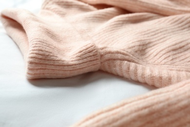 Photo of Stylish knitted sweater on white fabric, closeup