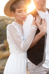 Photo of Happy bride and groom standing outdoors at sunset, closeup