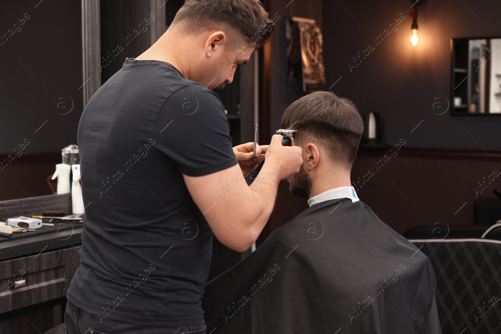 Photo of Professional hairdresser making stylish haircut in barbershop