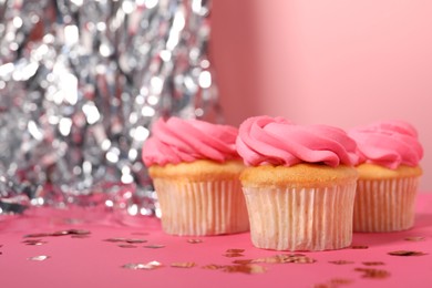 Photo of Delicious cupcakes with bright cream and confetti on pink background