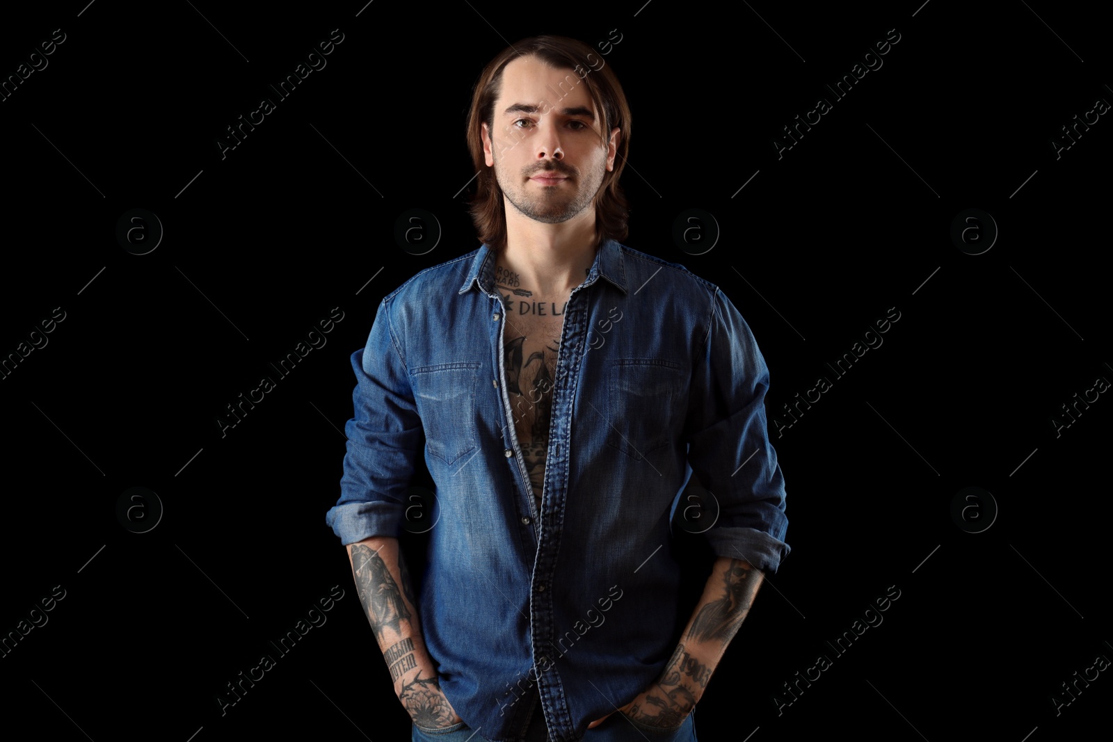 Photo of Young man with tattoos on body against black background