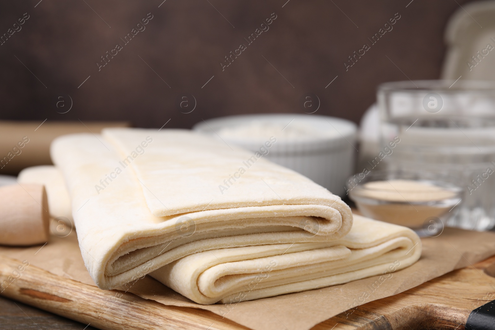 Photo of Raw puff pastry dough on wooden table, closeup