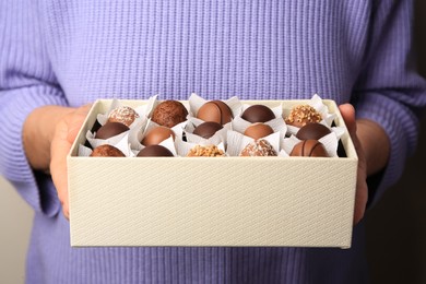 Photo of Woman holding box of delicious chocolate candies, closeup