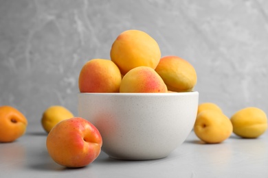 Photo of Many fresh ripe apricots on light grey table