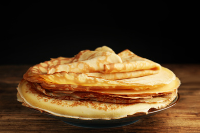 Photo of Stack of fresh thin pancakes on wooden table