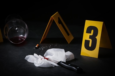 Photo of Knife and bloody napkin on black slate table at crime scene