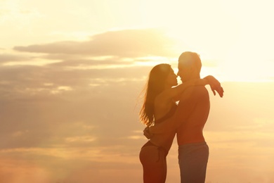 Young woman in bikini spending time with her boyfriend on beach. Lovely couple