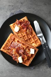 Photo of Tasty Belgian waffles served with bacon and butter on grey table, top view