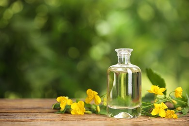 Photo of Bottle of natural celandine oil near flowers on wooden table outdoors, space for text