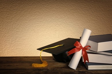 Image of Graduation hat, books and diploma on wooden table. Space for text