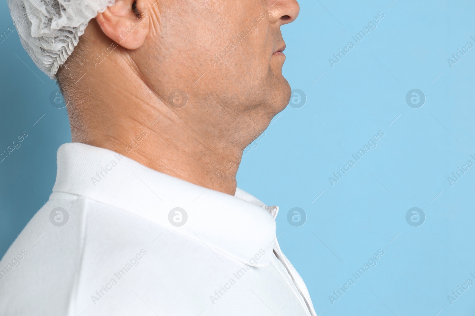 Photo of Mature man with double chin on blue background, closeup. Space for text