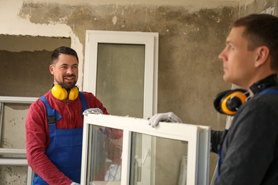 Photo of Workers in uniform with new plastic window indoors