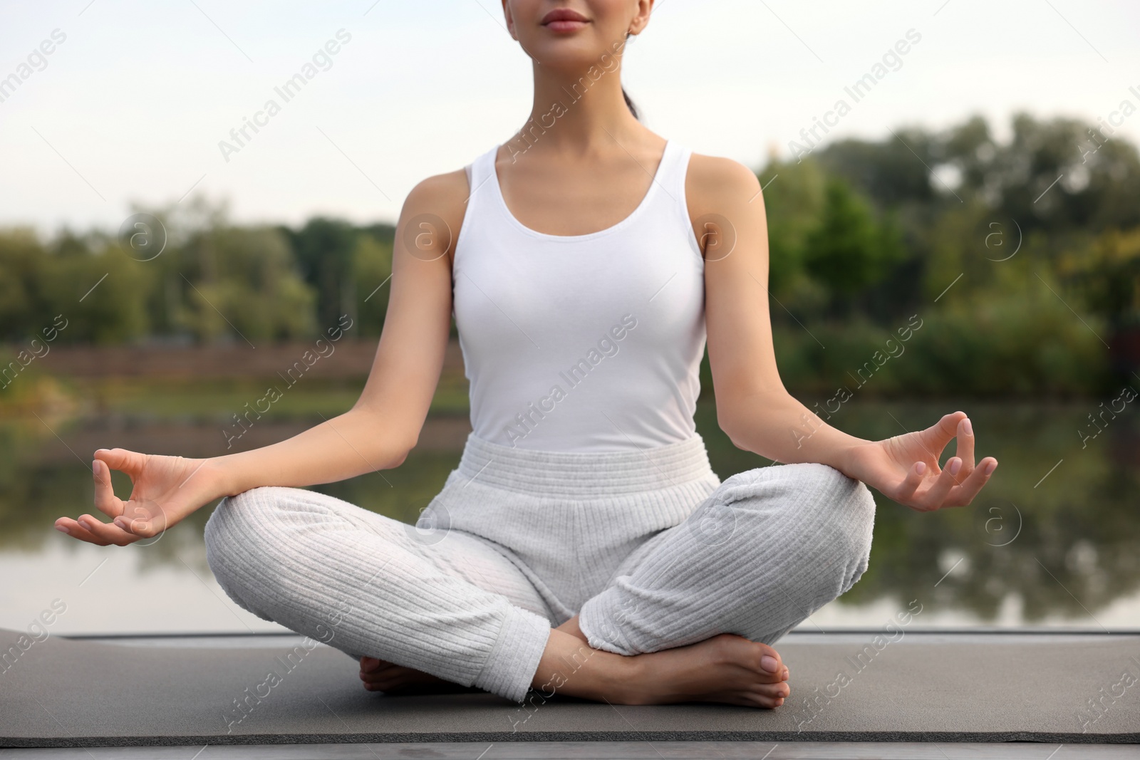 Photo of Woman practicing Padmasana on yoga mat outdoors, closeup. Lotus pose