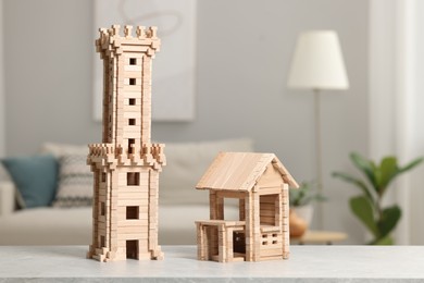 Photo of Wooden tower and house on light grey table indoors. Children's toys