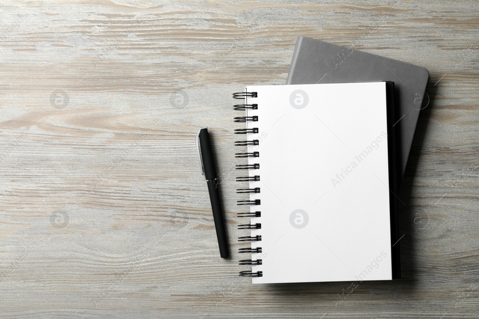 Photo of Stylish notebooks and pen on white wooden table, flat lay. Space for text