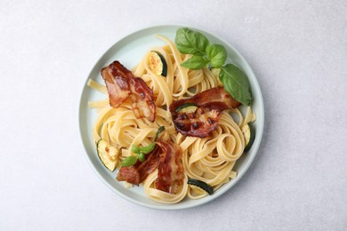 Photo of Tasty pasta with bacon and basil on light grey table, top view