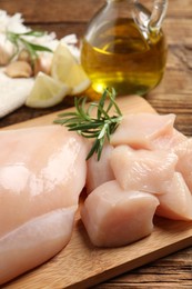 Photo of Fresh raw chicken breast with rosemary on wooden table, closeup