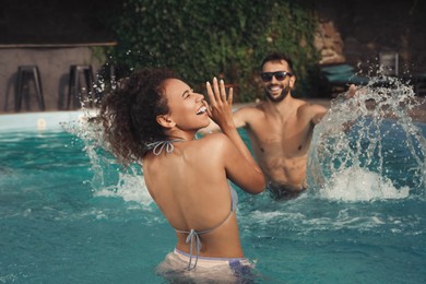 Photo of Happy couple having fun in outdoor swimming pool on sunny summer day