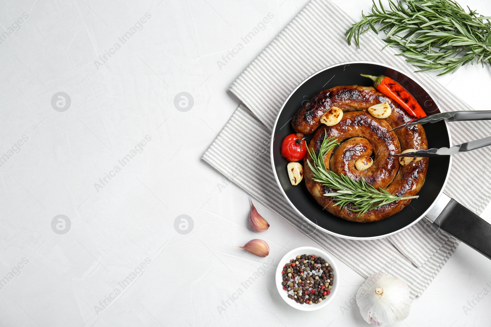 Photo of Delicious homemade sausage with garlic, tomato, rosemary and chili served on white table, flat lay. Space for text