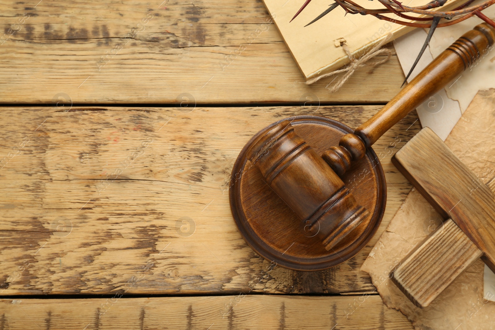 Photo of Judge gavel and cross on wooden table, flat lay. Space for text