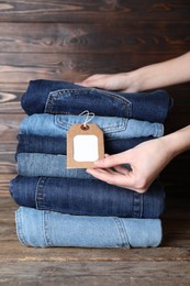 Woman folding stylish jeans on wooden table, closeup