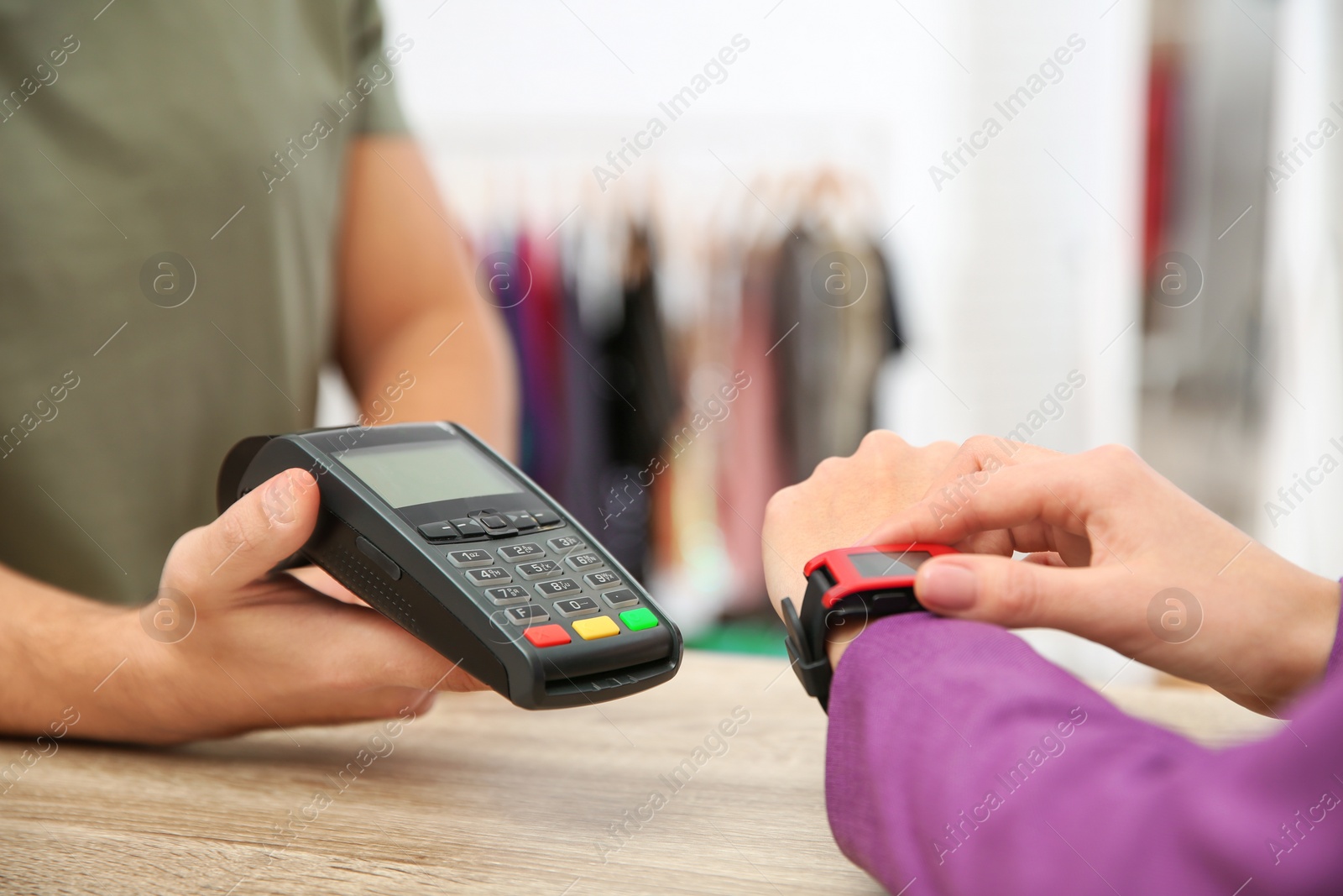 Photo of Woman using terminal for contactless payment with smart watch in shop, closeup