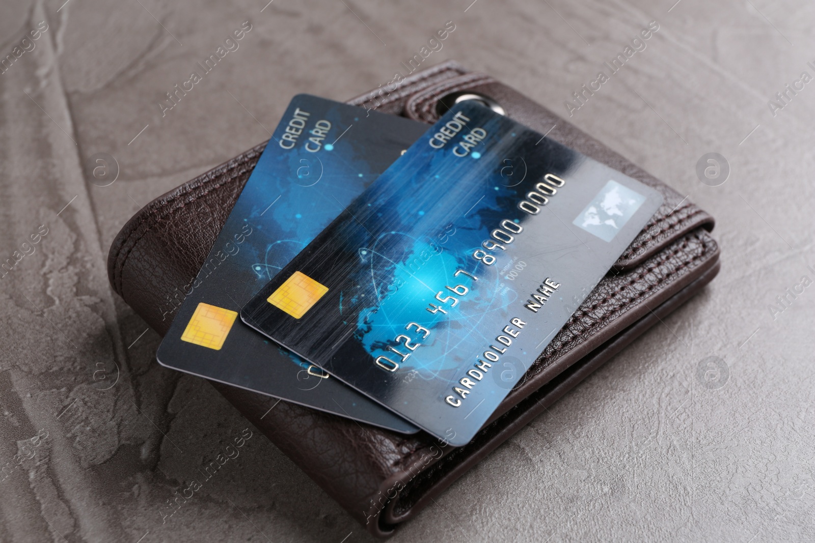 Photo of Credit cards and leather wallet on grey textured table, closeup