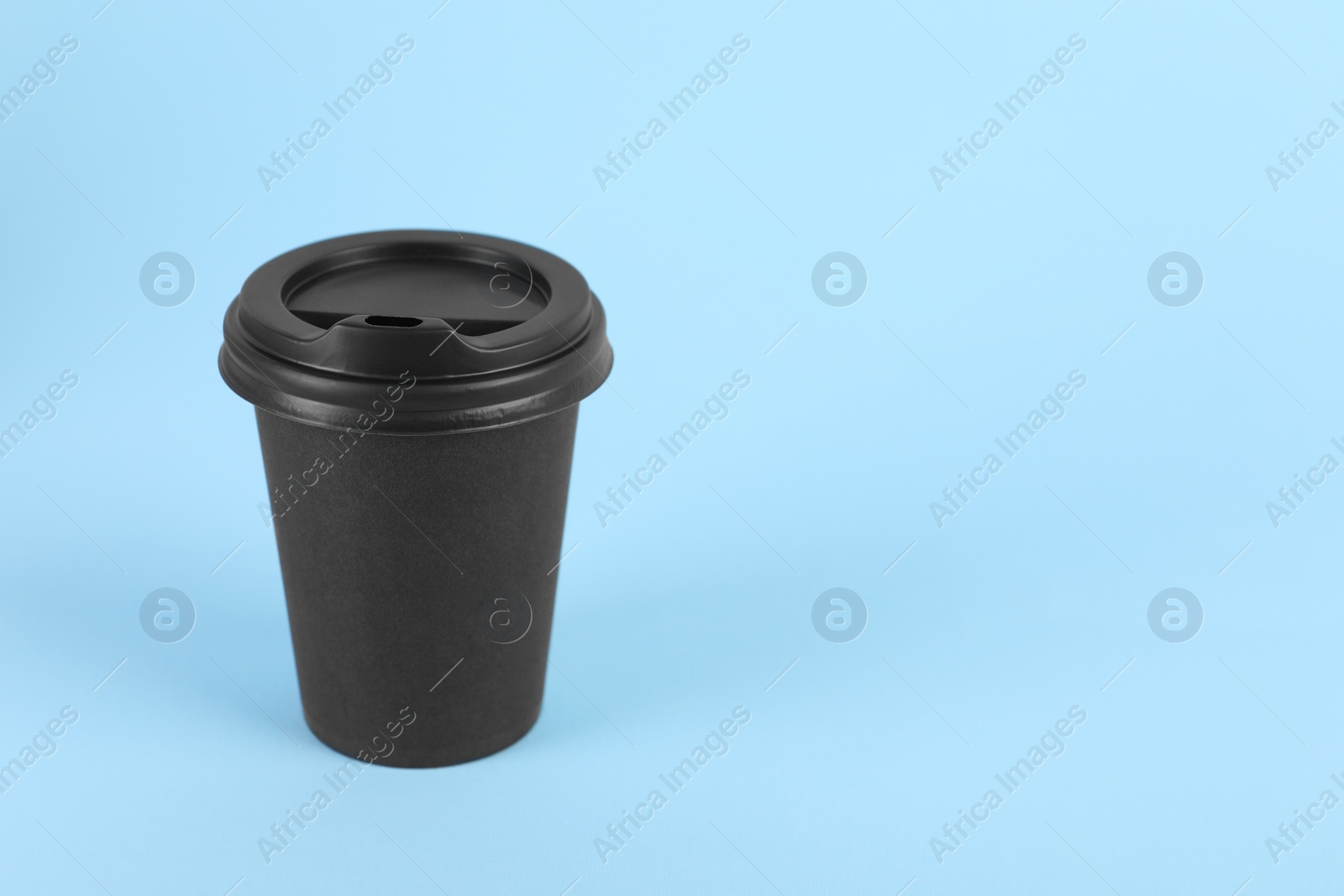 Photo of Black paper cup with plastic lid on light blue background, space for text. Coffee to go