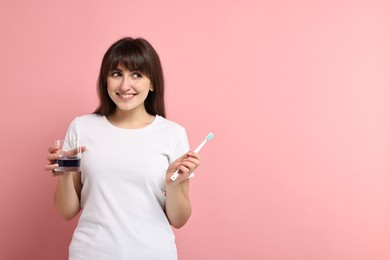 Photo of Young woman with mouthwash and toothbrush on pink background, space for text