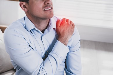 Man suffering from shoulder pain at home, closeup