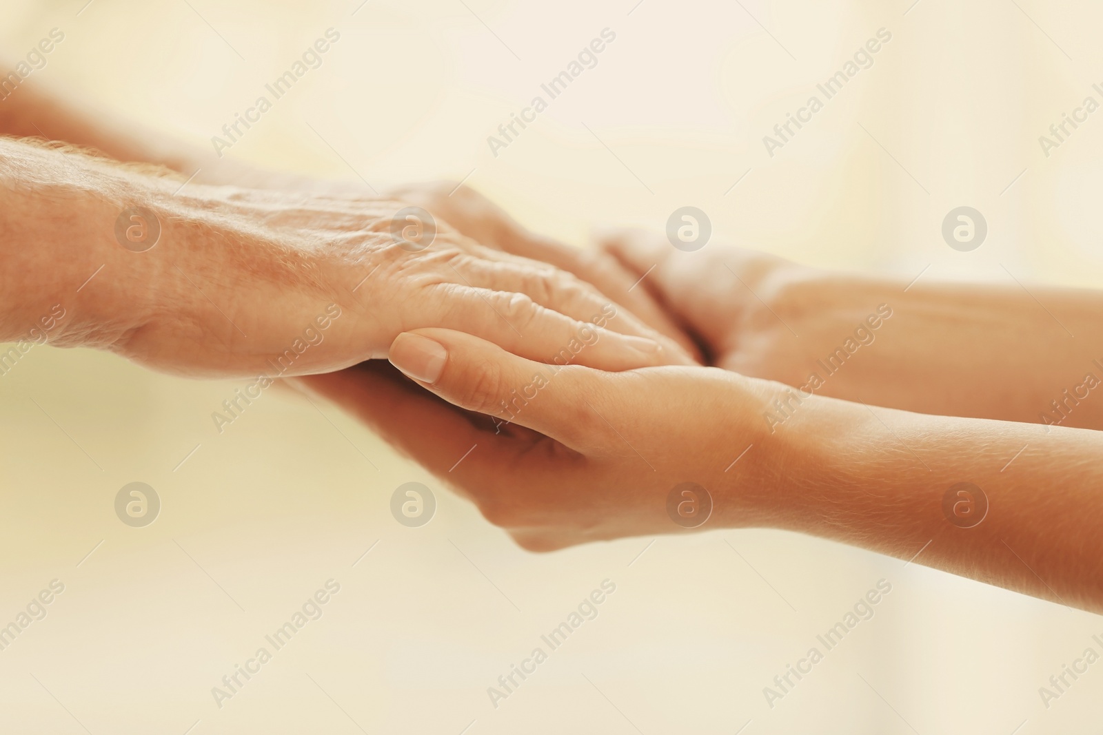 Image of Helping hands on blurred background, closeup. Elderly care concept