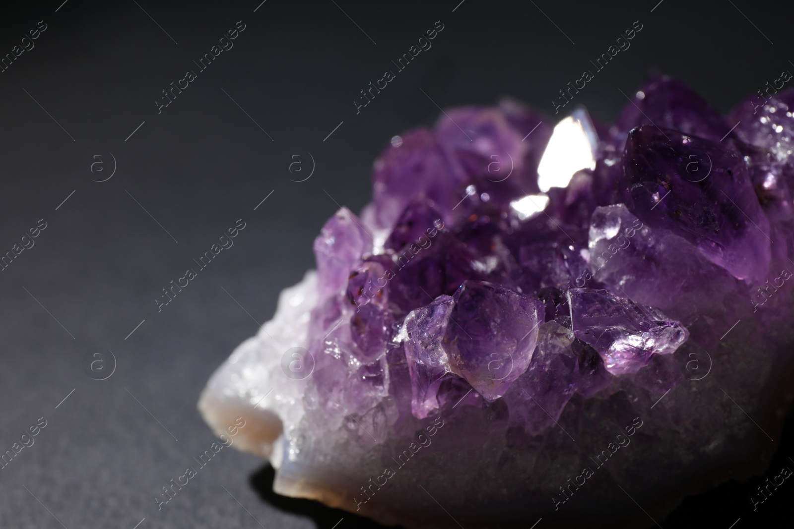 Photo of Beautiful amethyst on grey table, closeup. Healing crystal