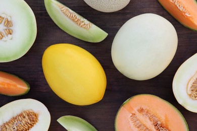 Different types of tasty ripe melons on wooden table, flat lay