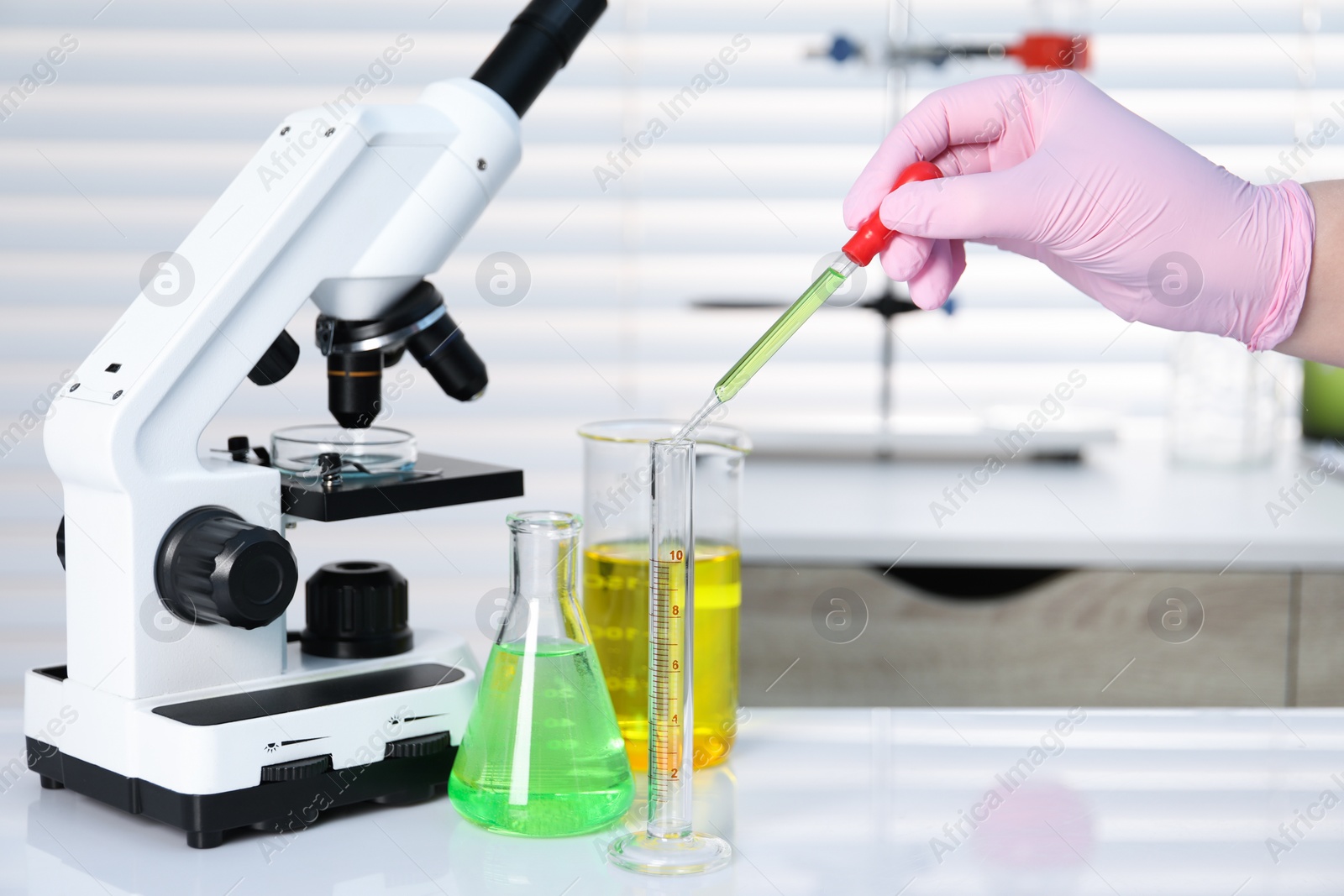 Photo of Laboratory analysis. Woman dripping liquid into test tube on white table indoors, closeup