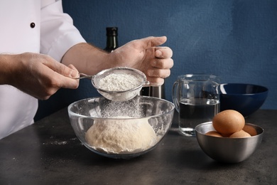 Photo of Man sprinkling dough for pastry with flour on table