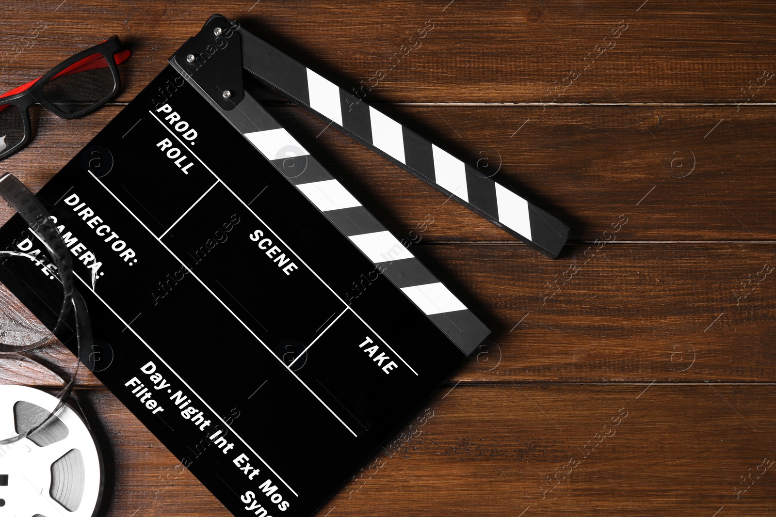 Photo of Clapperboard, film reel and 3D glasses on wooden table, flat lay. Space for text